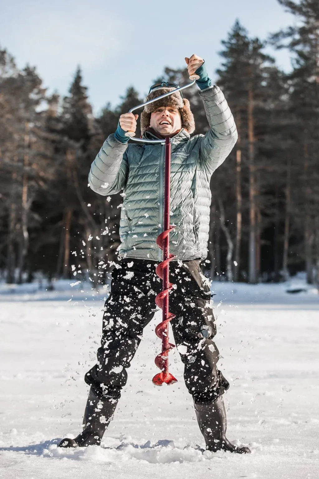 Wild About Lapland owner Theo Turner using an ice auger in Lapland