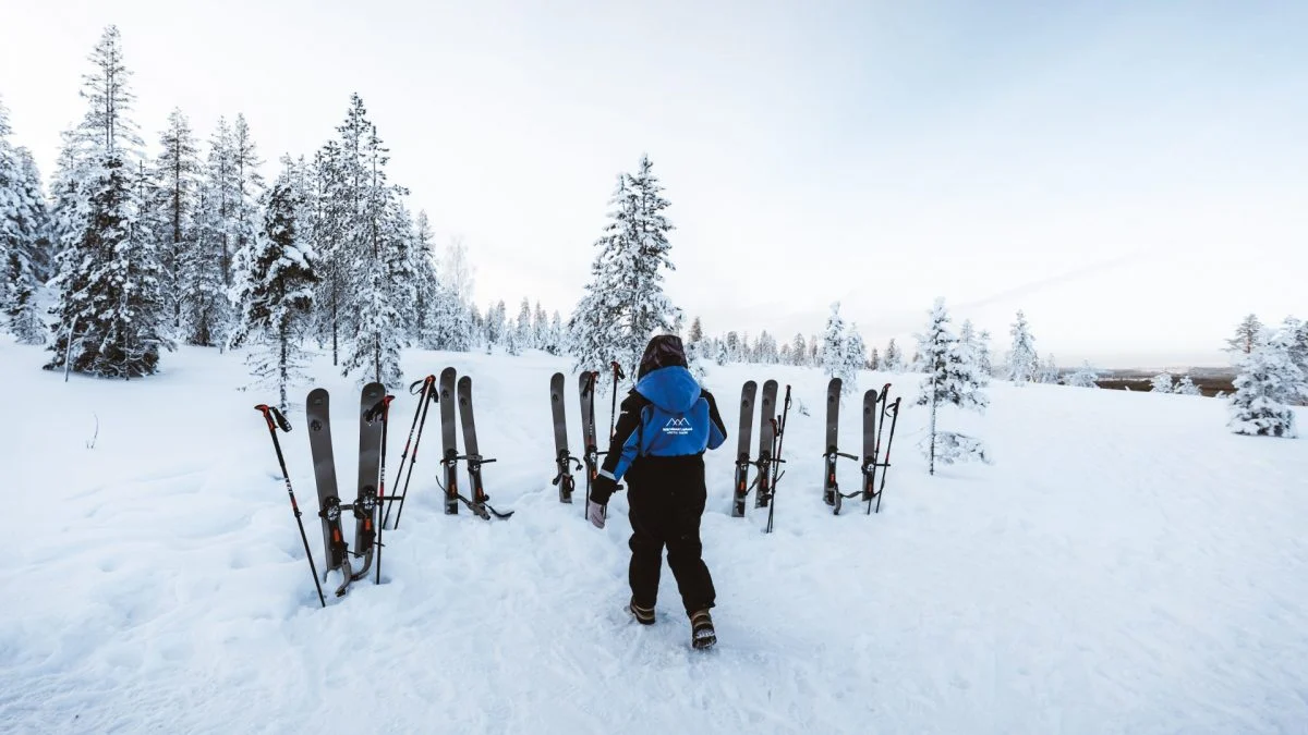 Wild About Lapland guide walking toward skis in a snowy forest