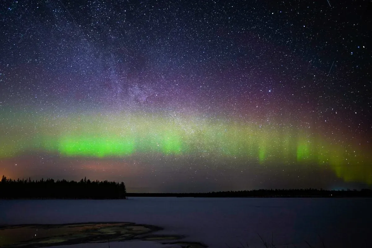 Northern lights and the Milky Way above a frozen lake in Lapland